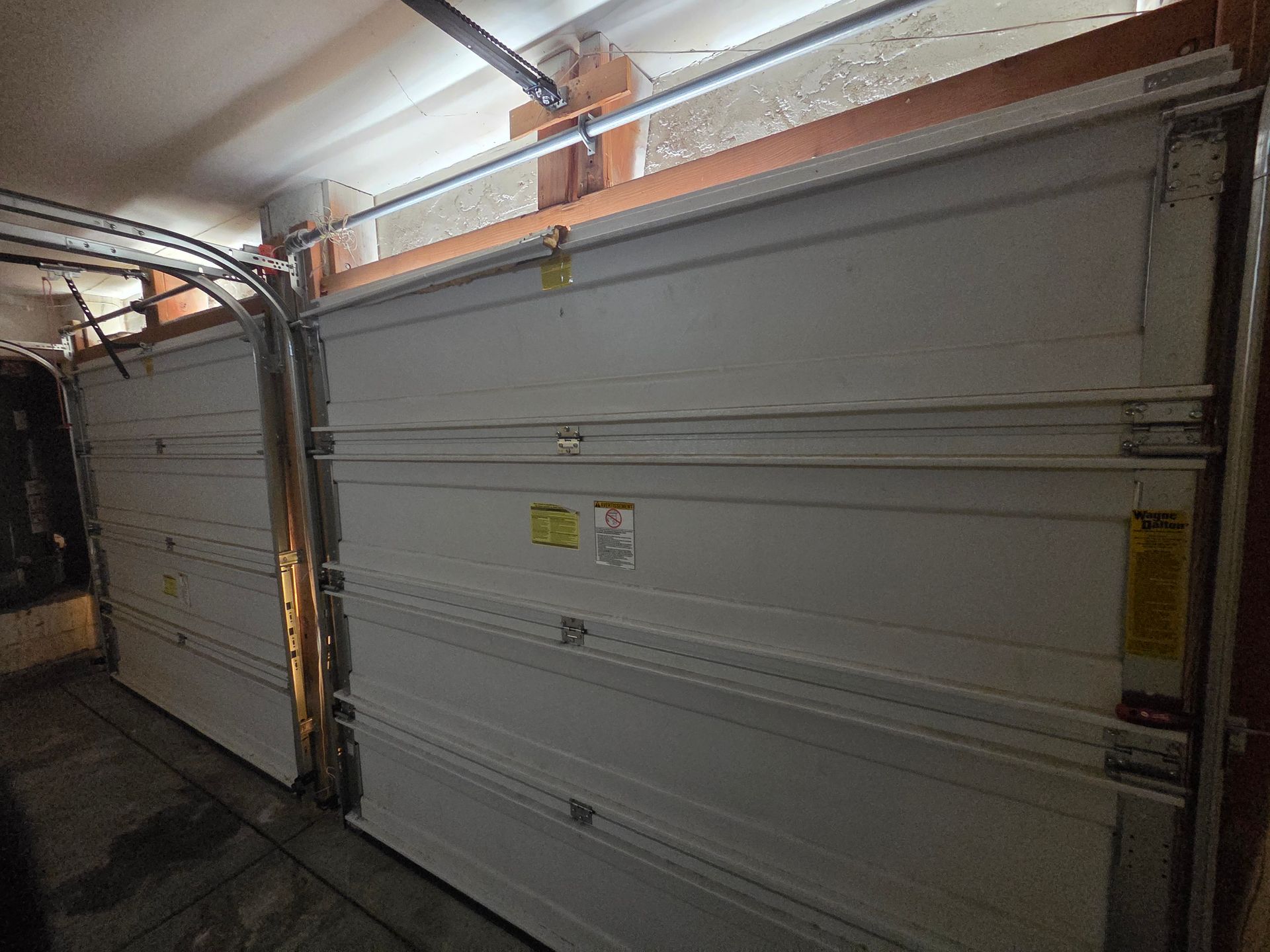 Indoor garage with two white overhead doors and exposed ceiling tracks