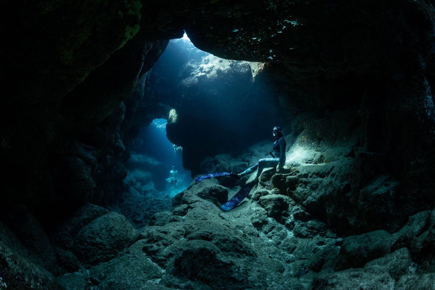 A freediver is swimming in a cave underwater.