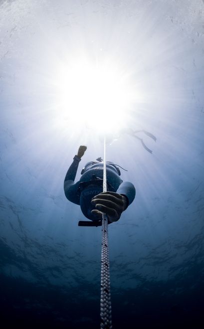 A freedriver going down in the water holding a rope.