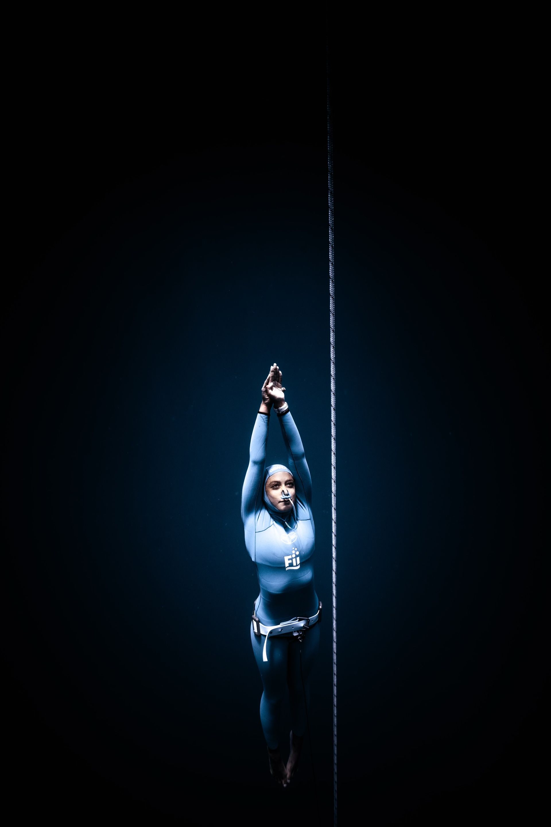 A woman in a blue suit freediving in the ocean.