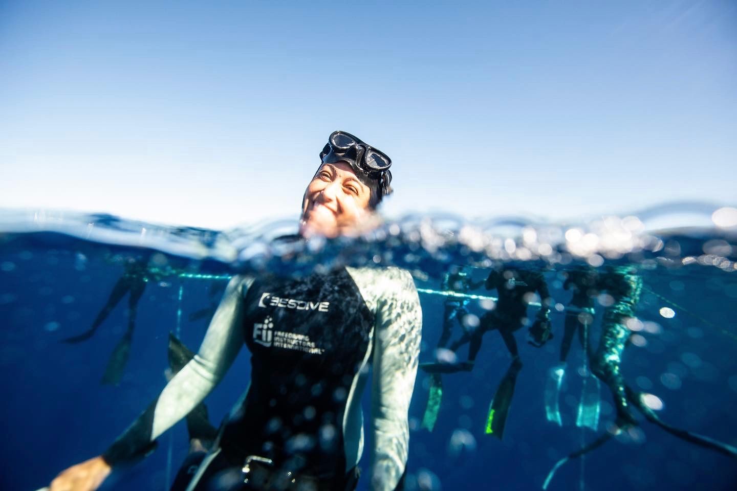 A woman in a wetsuit is freediving in the ocean.