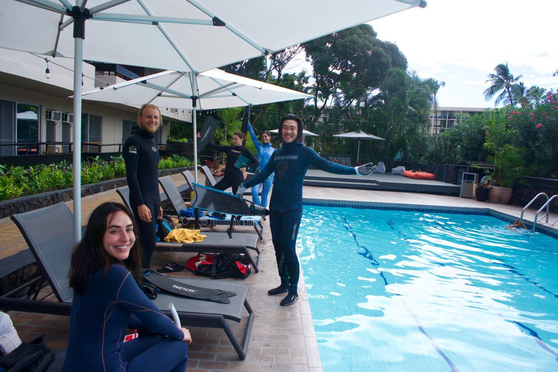 A group of people are standing next to a swimming pool.