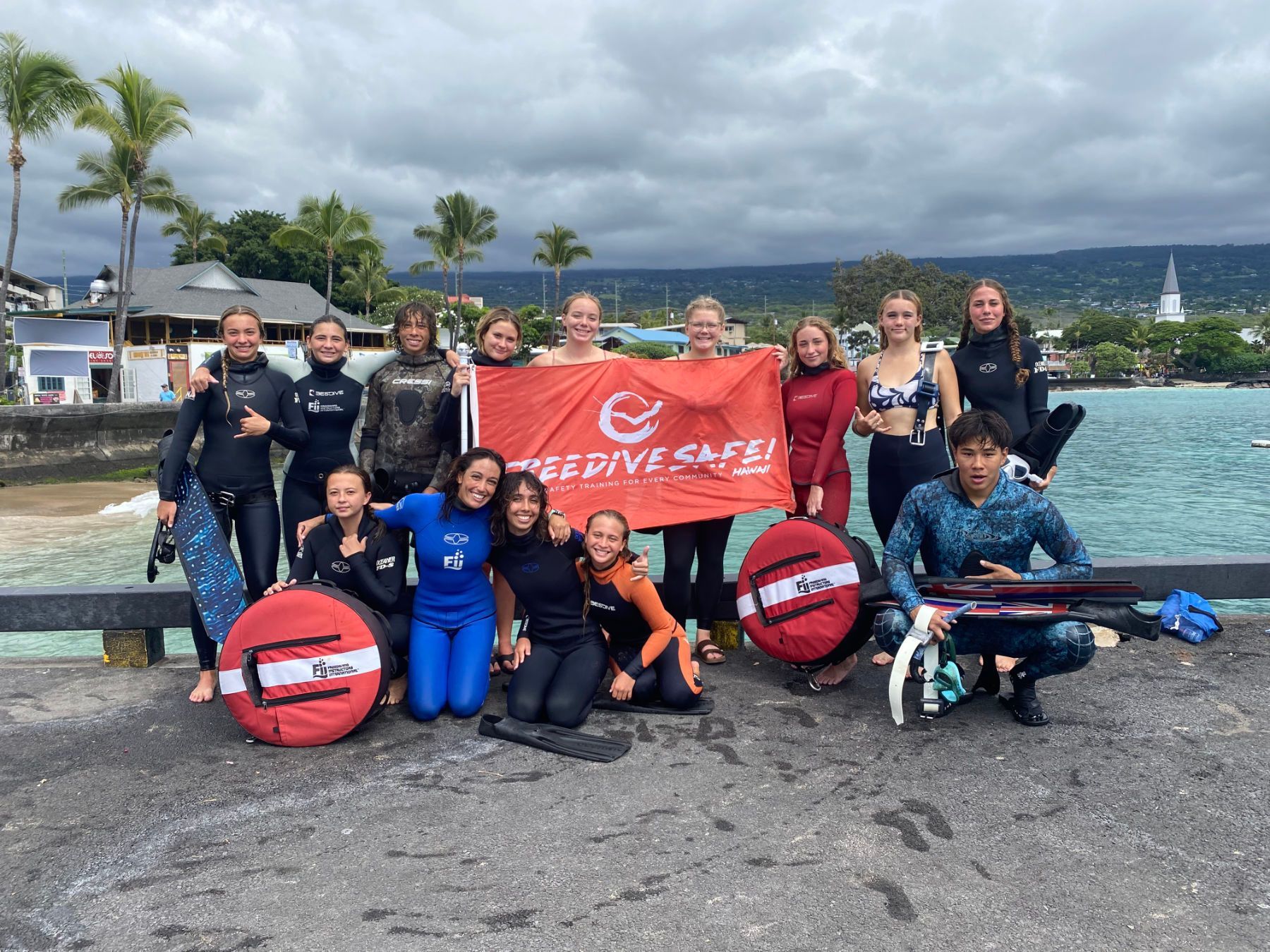 A group of people are posing for a picture while holding a freedive safe flag.