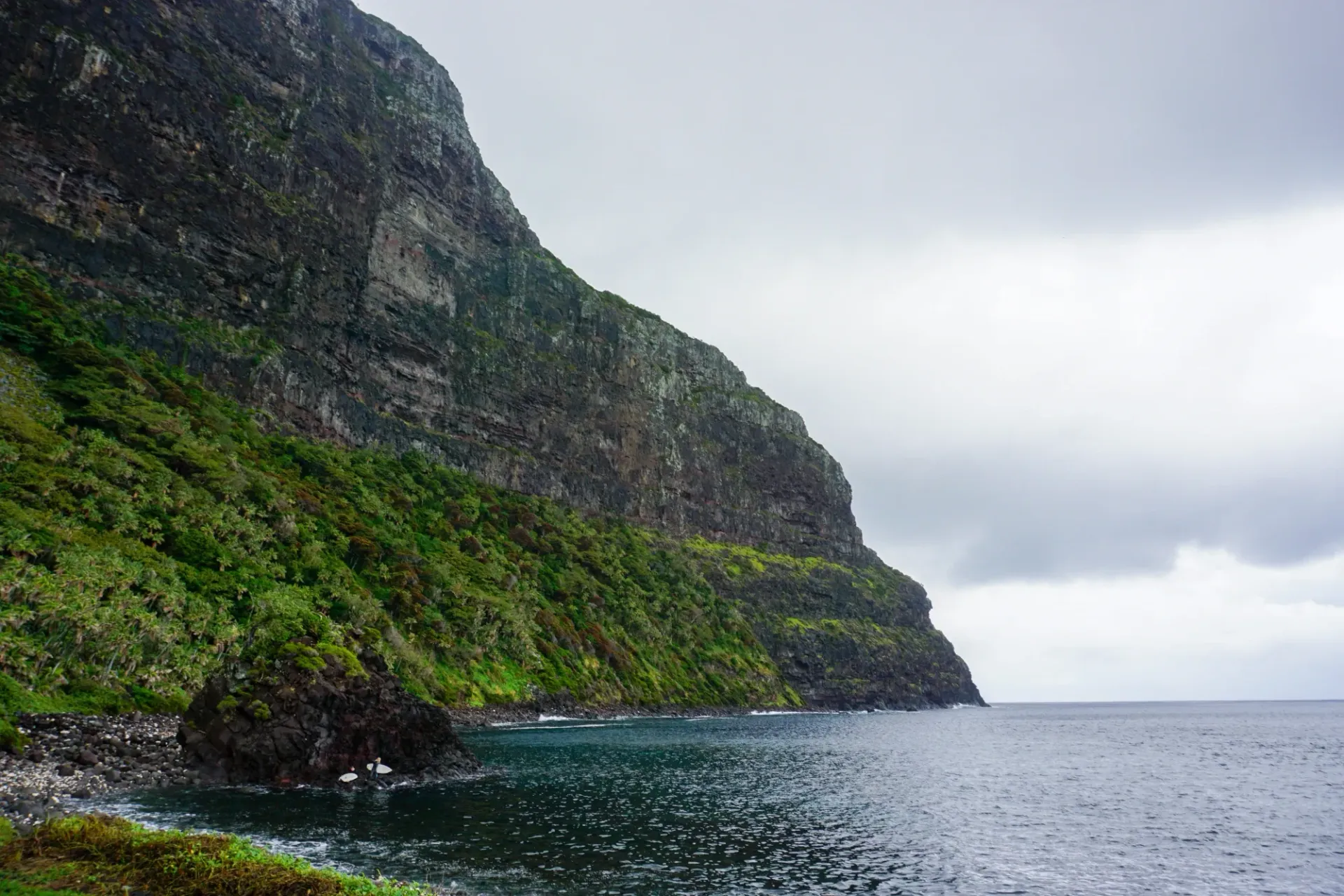 A cliff overlooking a body of water with a mountain in the background