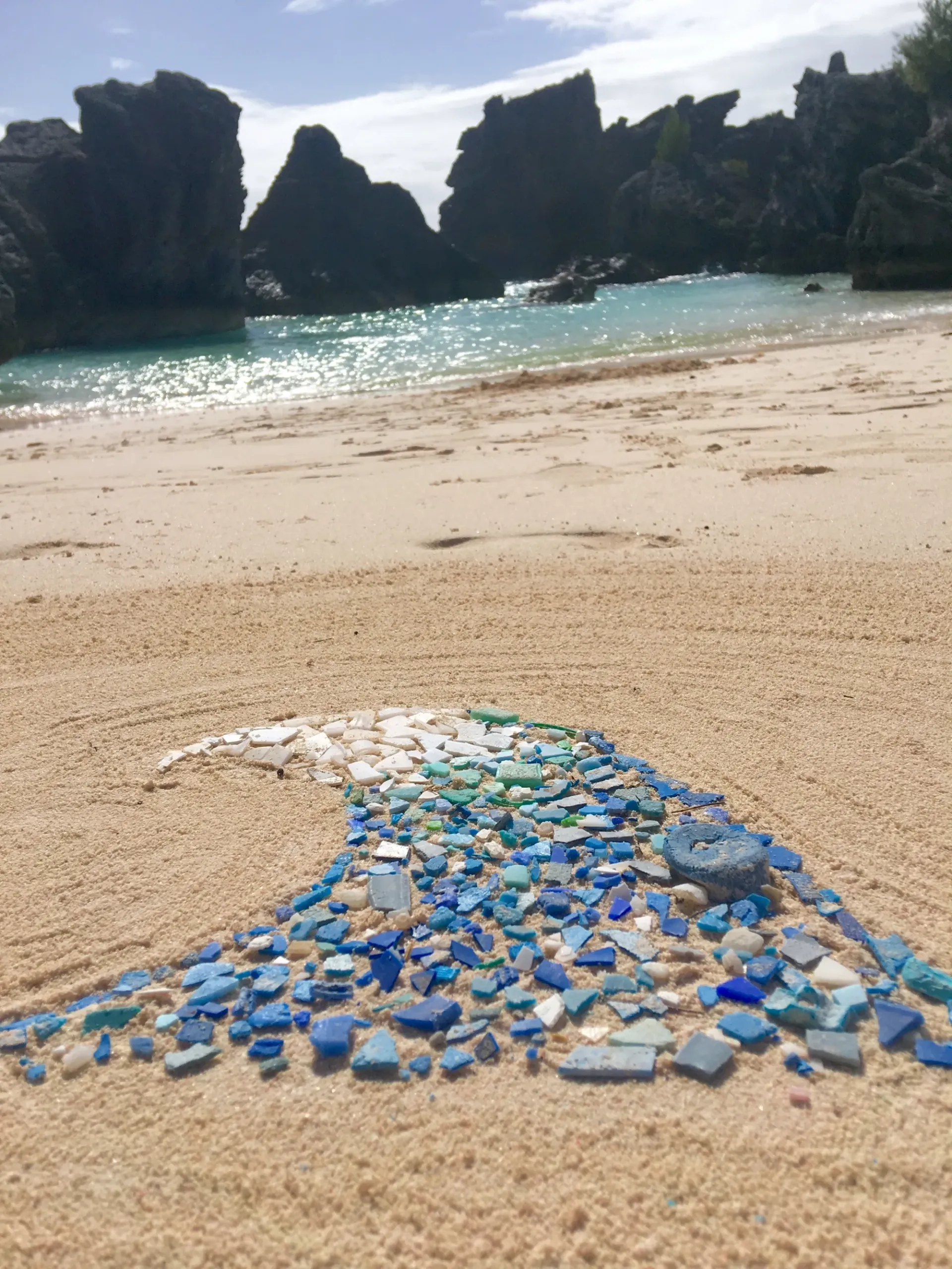 A wave made out of sea glass on a sandy beach.