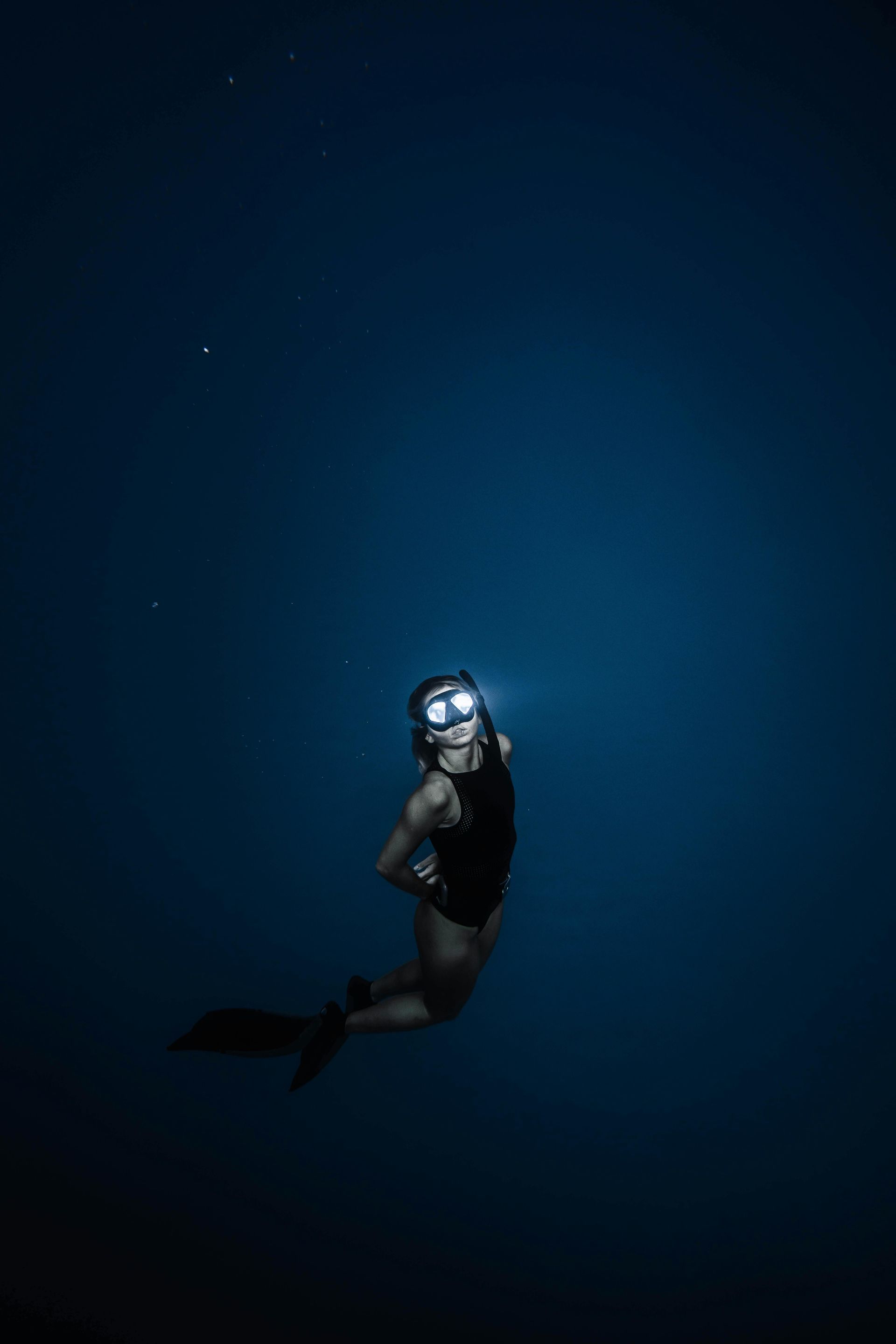 A scuba diver is freediving in the ocean at night.