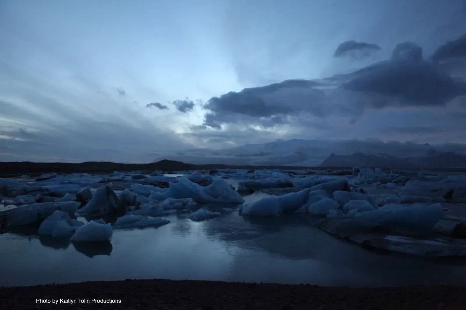 A large body of water filled with ice and mountains in the background