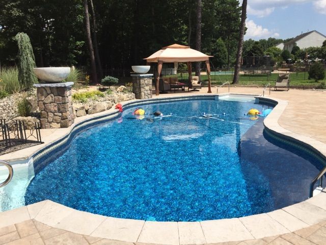 A large swimming pool with a gazebo in the background