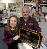A man and a woman are holding a plaque in a room.