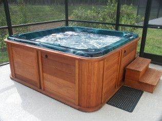 A wooden hot tub is sitting on a screened in porch.