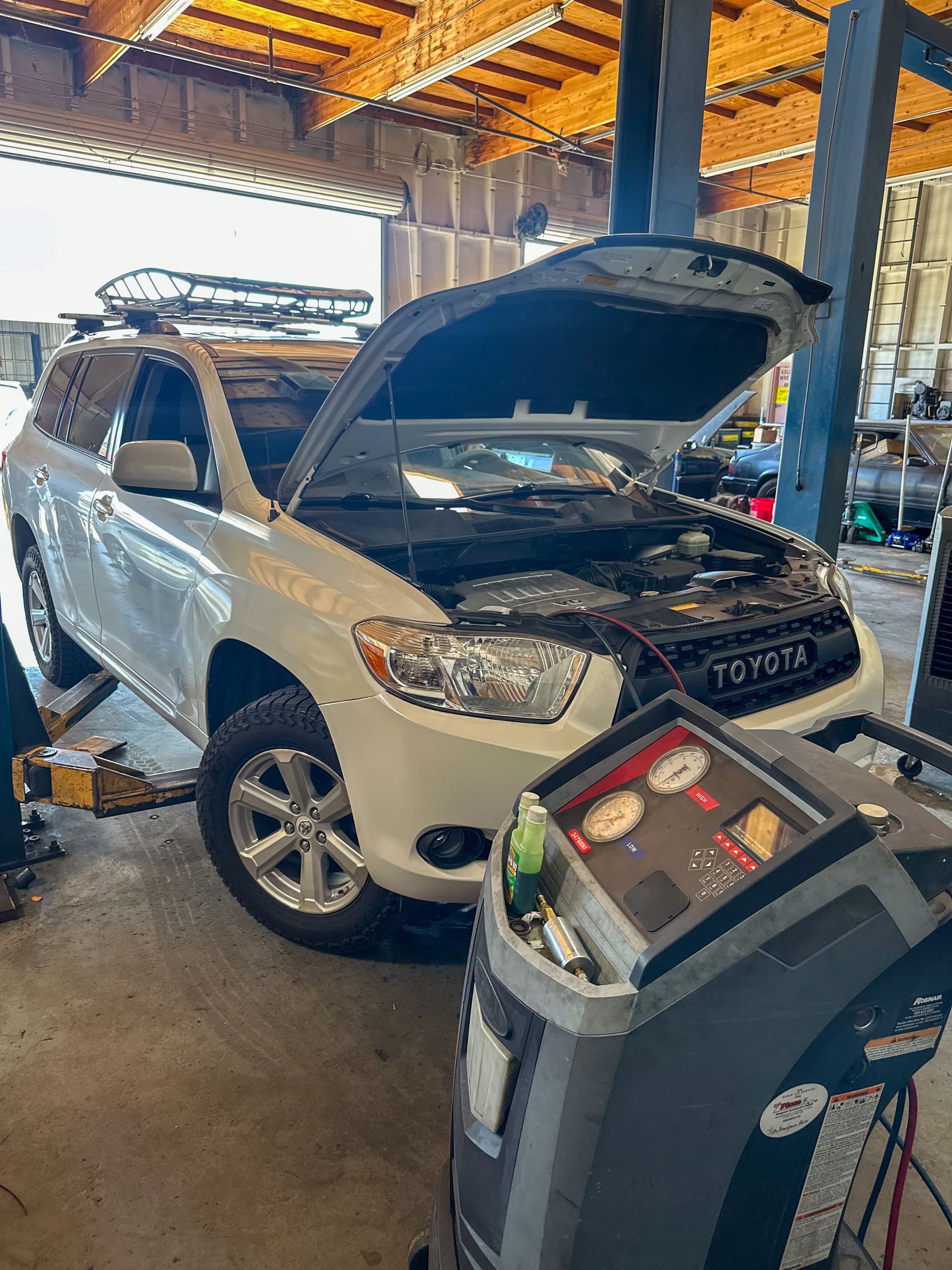 White Toyota SUV with hood open in a repair shop, being serviced with a machine. | Jim Brangham Auto Repair