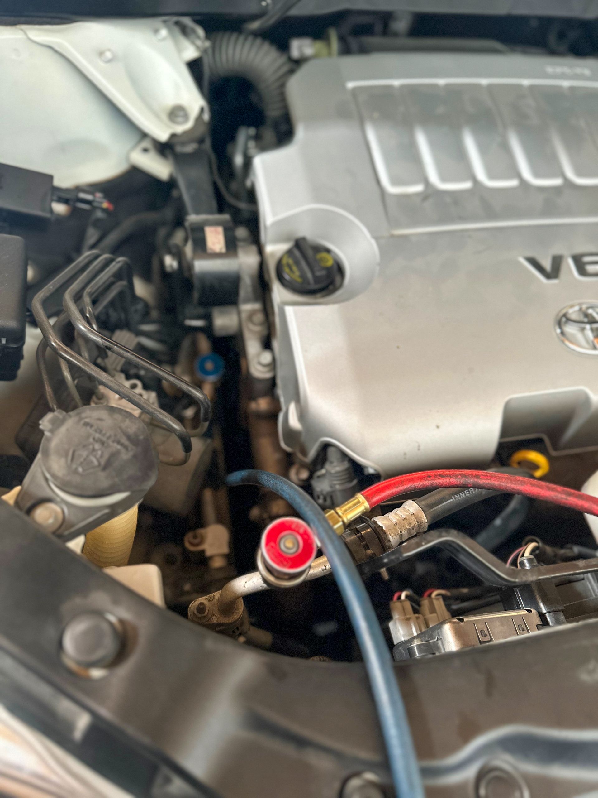 A car engine with a blue hose attached, checking the AC system. | Jim Brangham Auto Repair