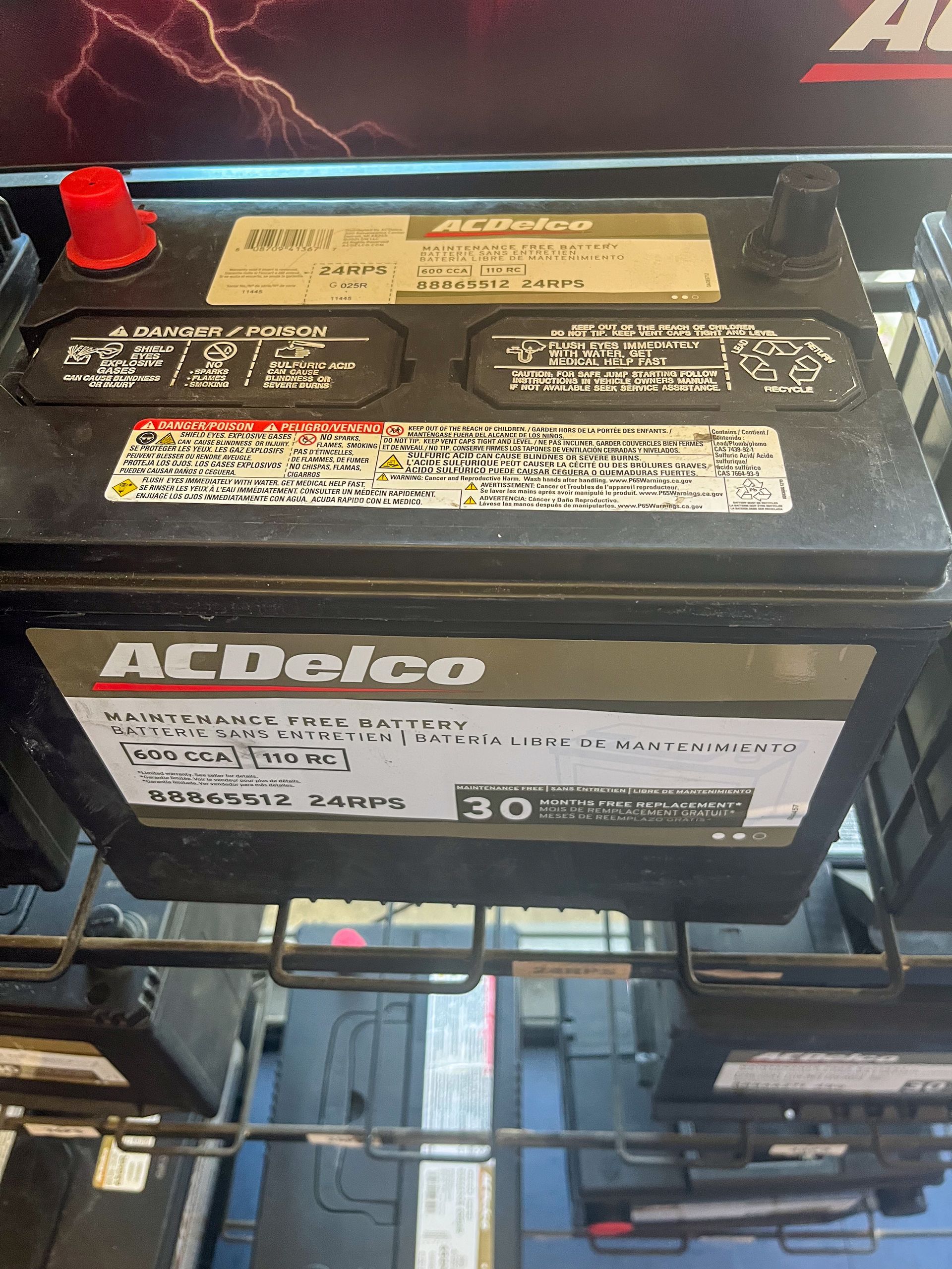ACDelco car battery in a display rack, with visible labels and terminals. | Jim Brangham Auto Repair