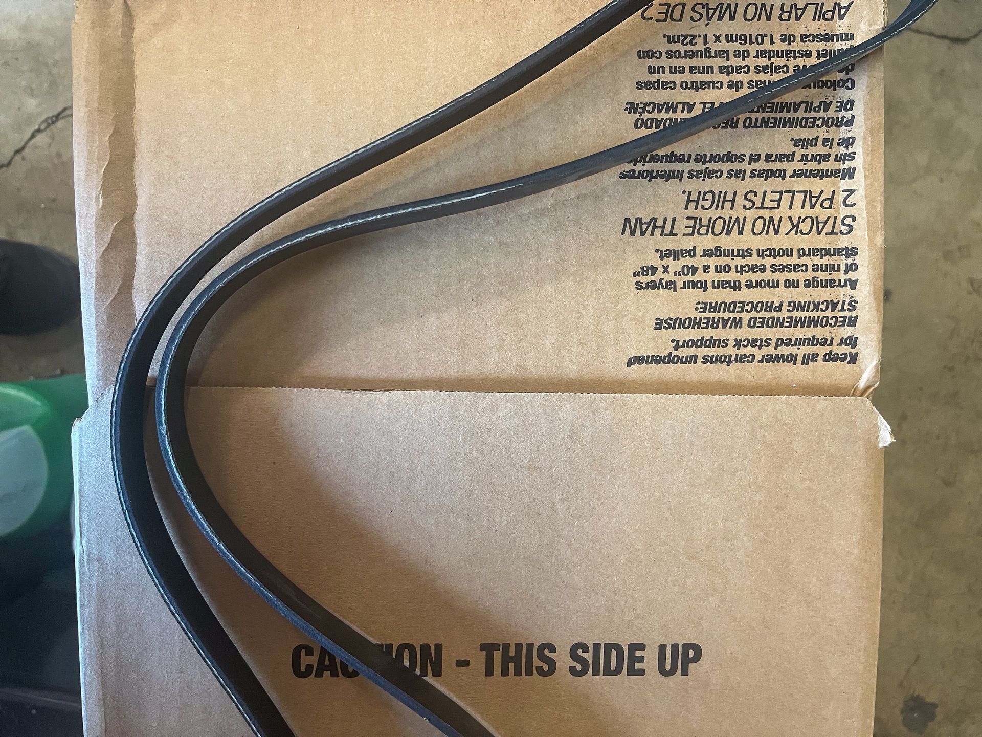 Black cables coiled on a cardboard box. Box has printed text and a 