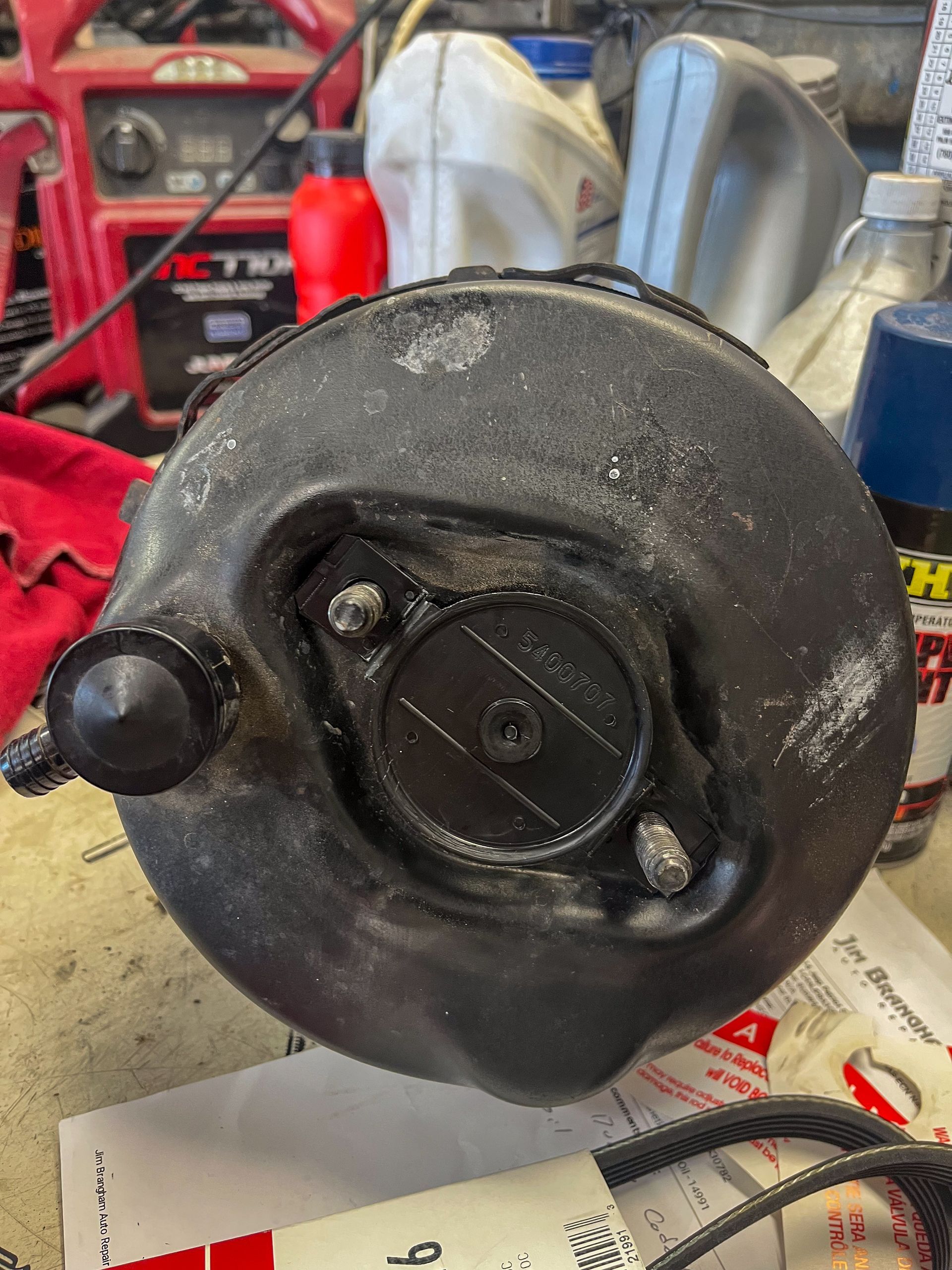 Black car brake booster, with studs, on a workbench. | Jim Brangham Auto Repair