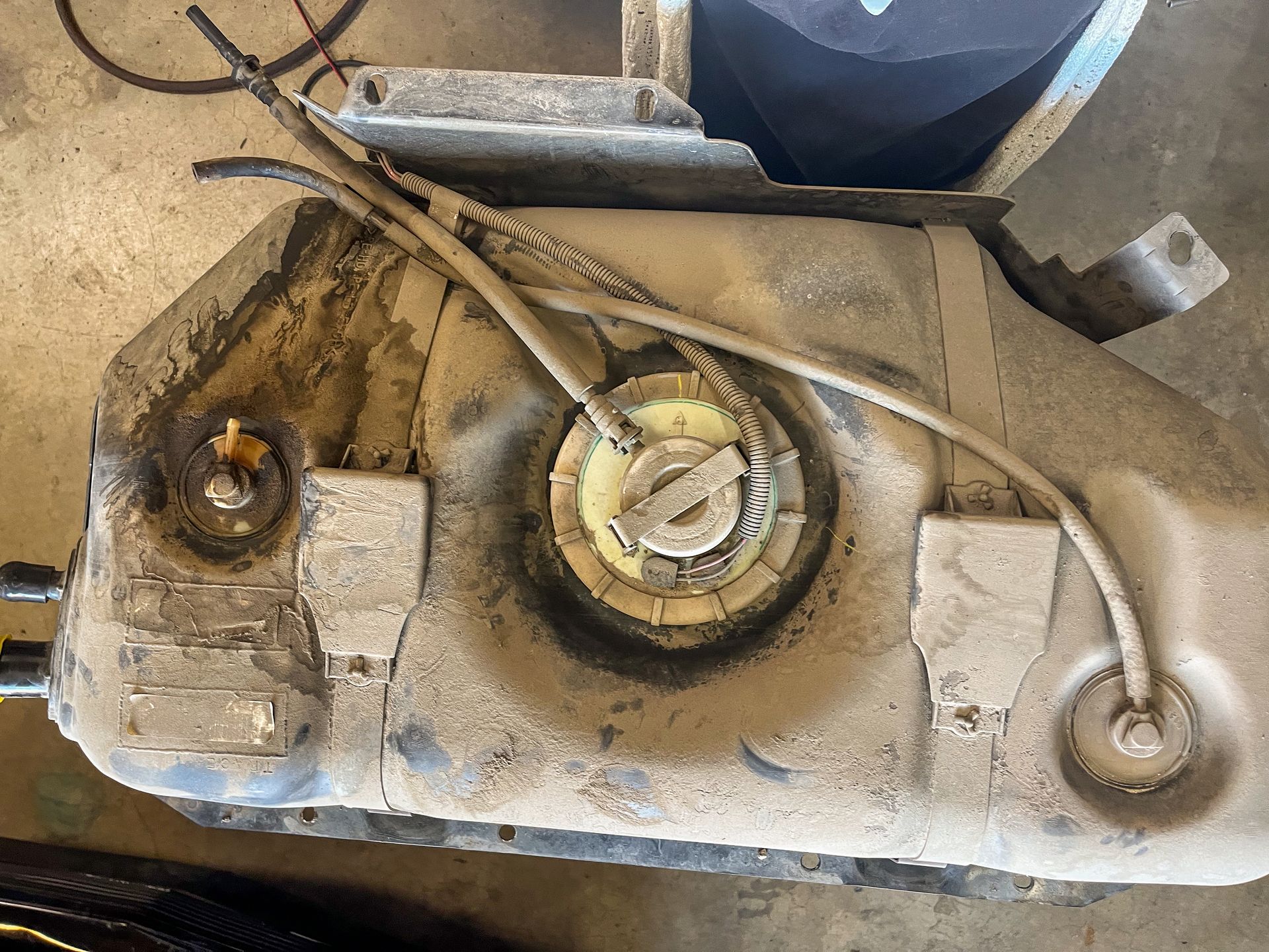 Dirty vehicle fuel tank with hoses and fuel pump access. | Jim Brangham Auto Repair