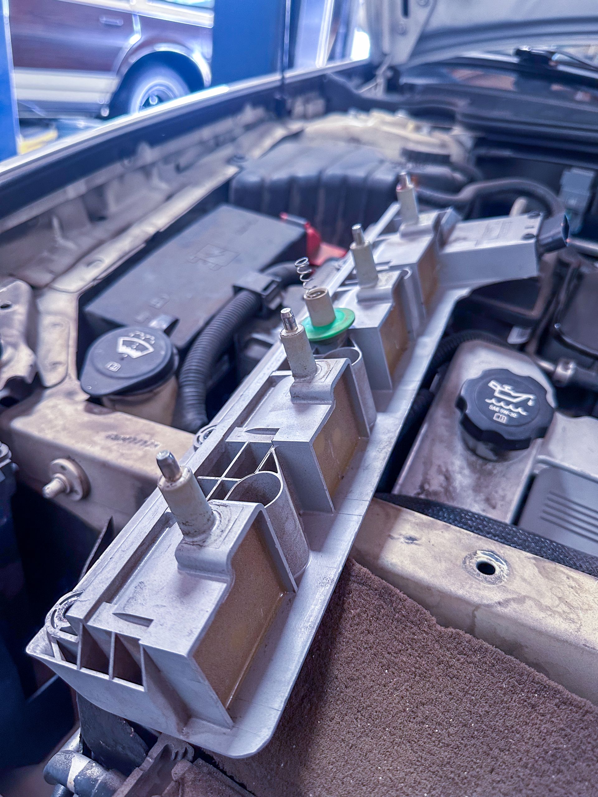 Car engine bay with a gray panel holding several brown and green light sockets. | Jim Brangham Auto Repair