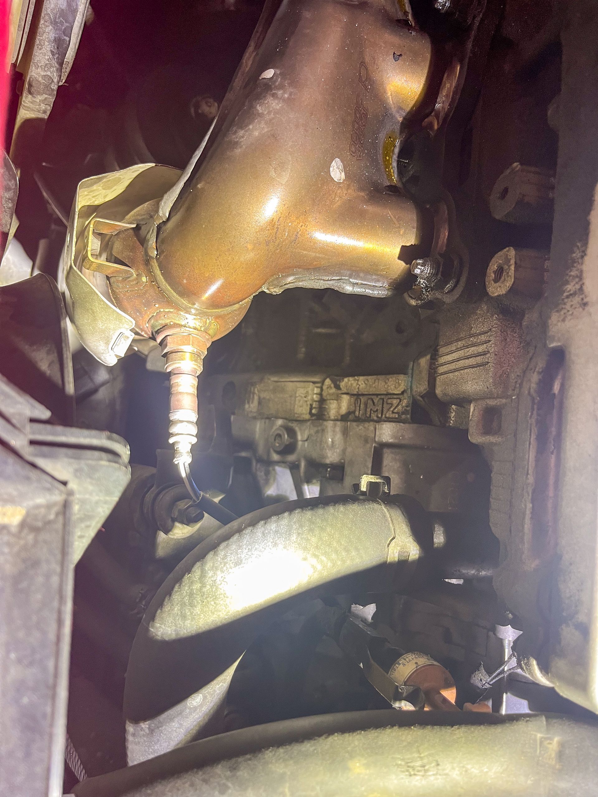 Catalytic converter and oxygen sensor under a vehicle, metallic brown and black. | Jim Brangham Auto Repair
