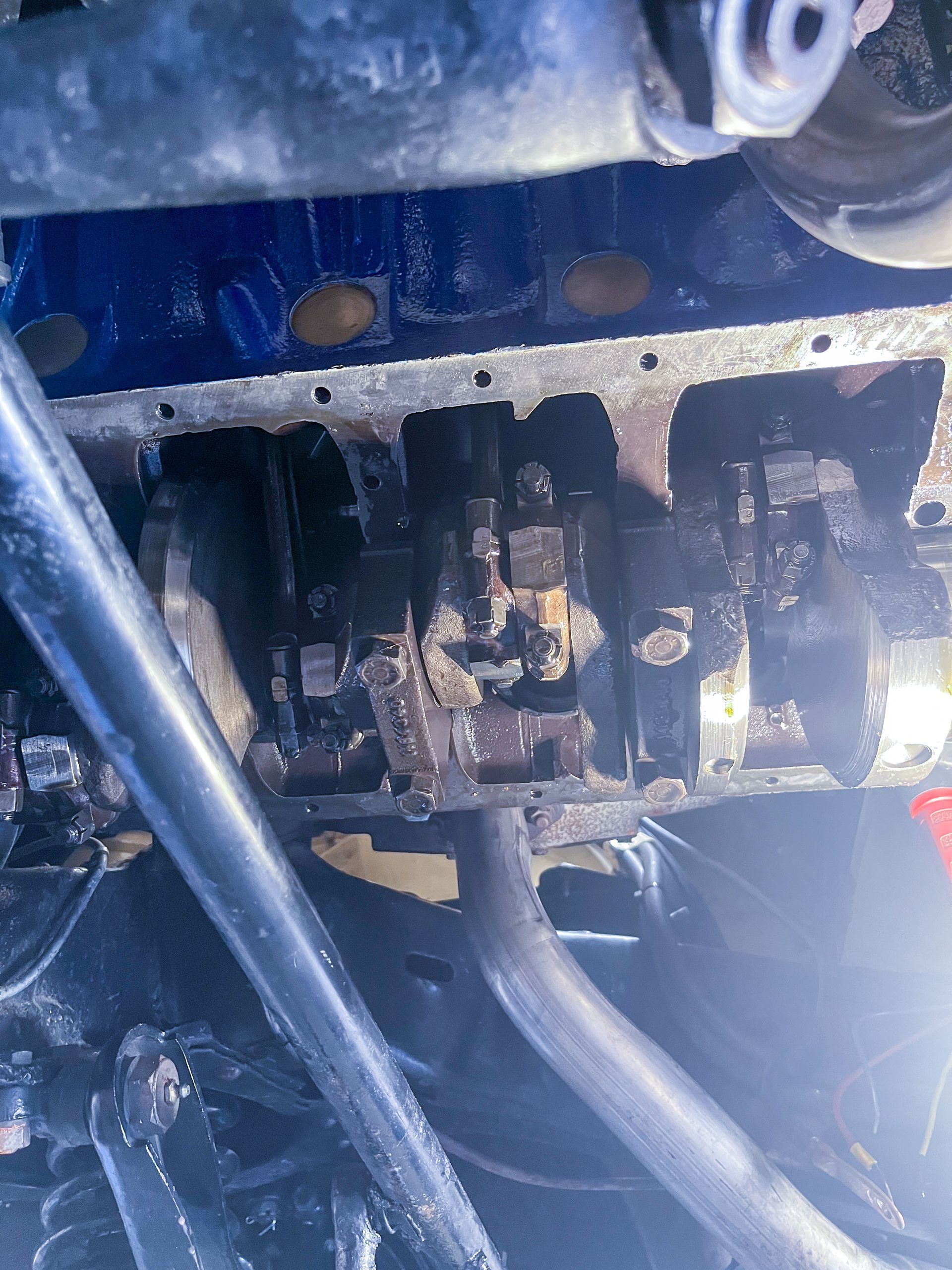 Engine's open bottom, revealing pistons, crankshaft, and oil, covered in grease. | Jim Brangham Auto Repair