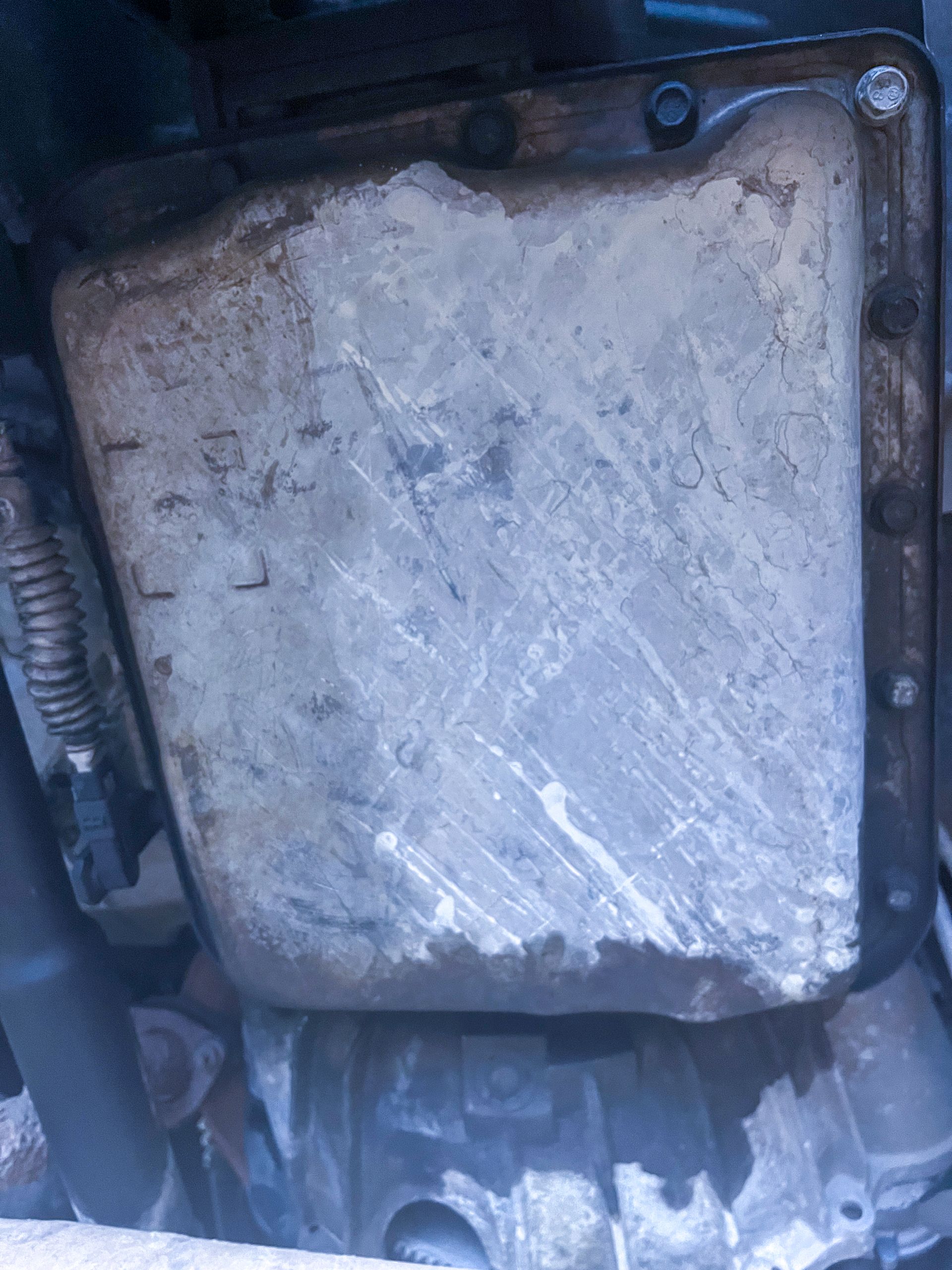 Oil pan of a vehicle, showing signs of wear and possibly rust. | Jim Brangham Auto Repair