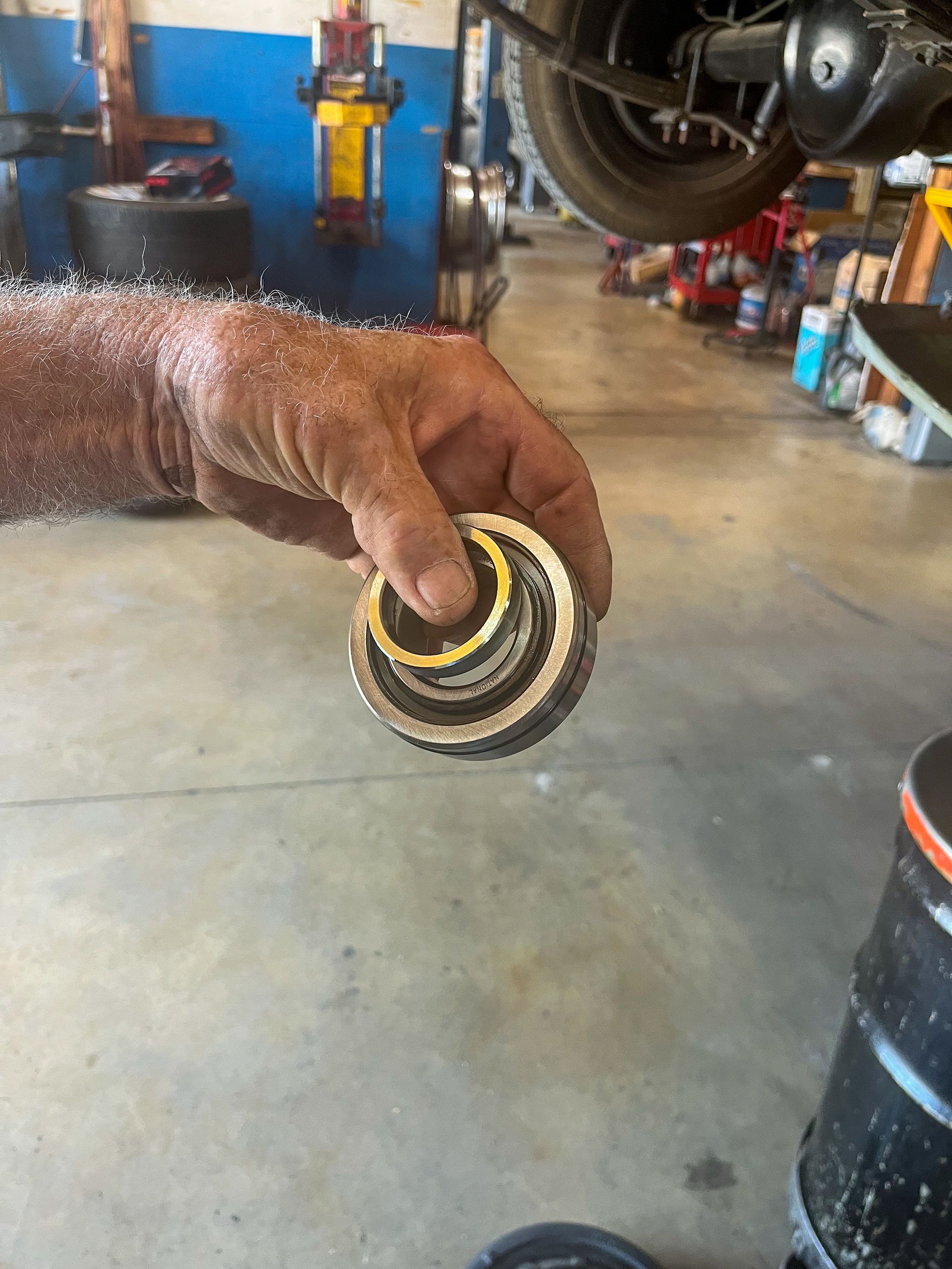A person's hand holding a damaged bearing in an auto repair shop. | Jim Brangham Auto Repair