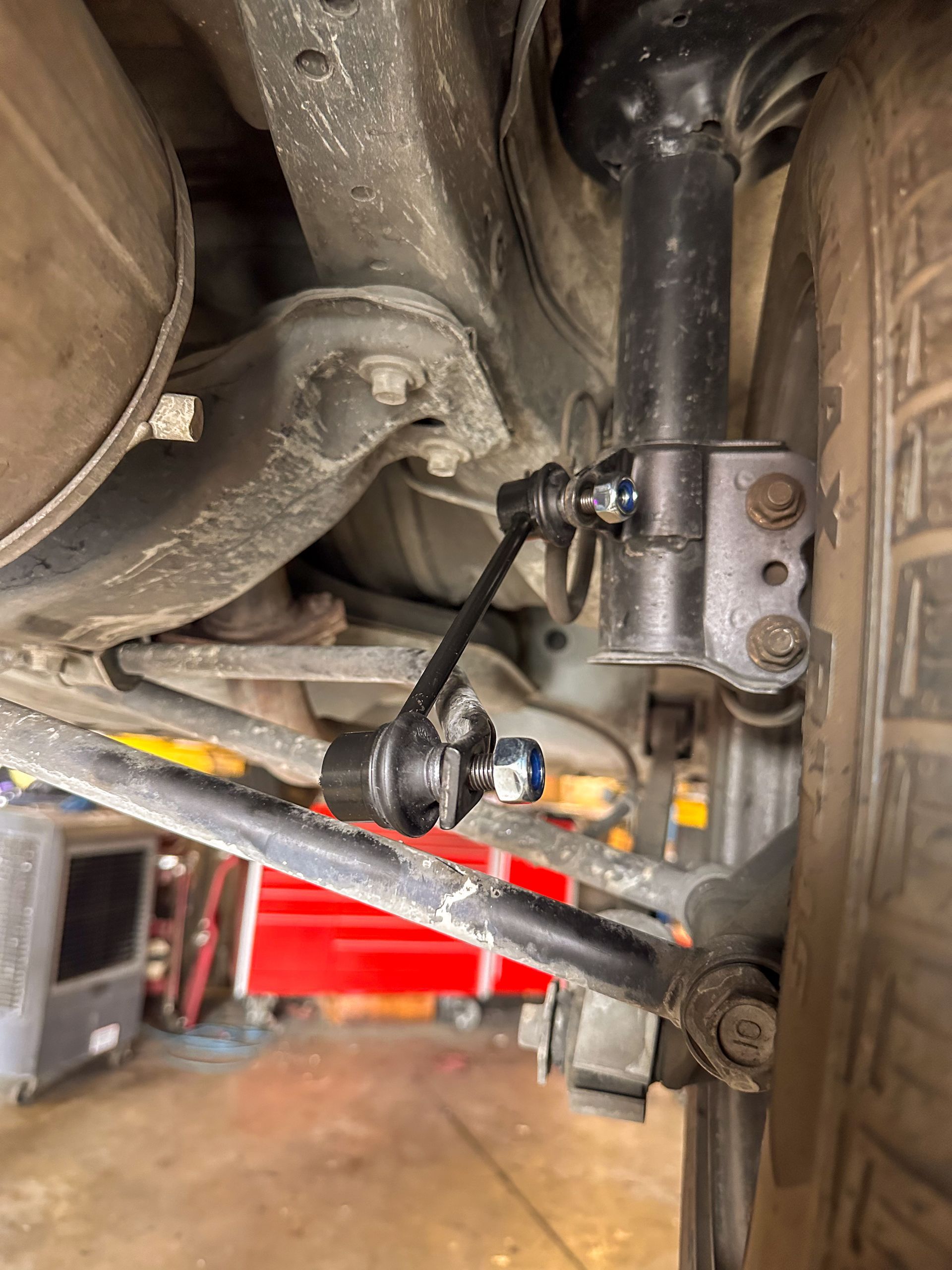 Underneath view of a car's rear suspension with a new sway bar link attached. | Jim Brangham Auto Repair