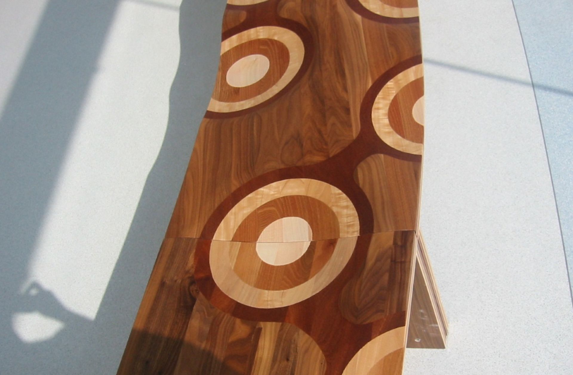 Ripples, winner of the 2004 Compasso d’Oro, is made of a laminated composite of five different solid woods. Slide your hand along the surface to enjoy the seamless transitions between walnut, mahogany, cherry, oak, and ash. This enveloping seat, carved with mastery, is hand-finished to produce an elegant polychromatic effect arising from the ductility of the wood. A true icon of international design, Ripples is a bench suitable for home users, commercial environments, and public spaces. The “Like a River” variant is a system of two modules with limitless composition possibilities.
