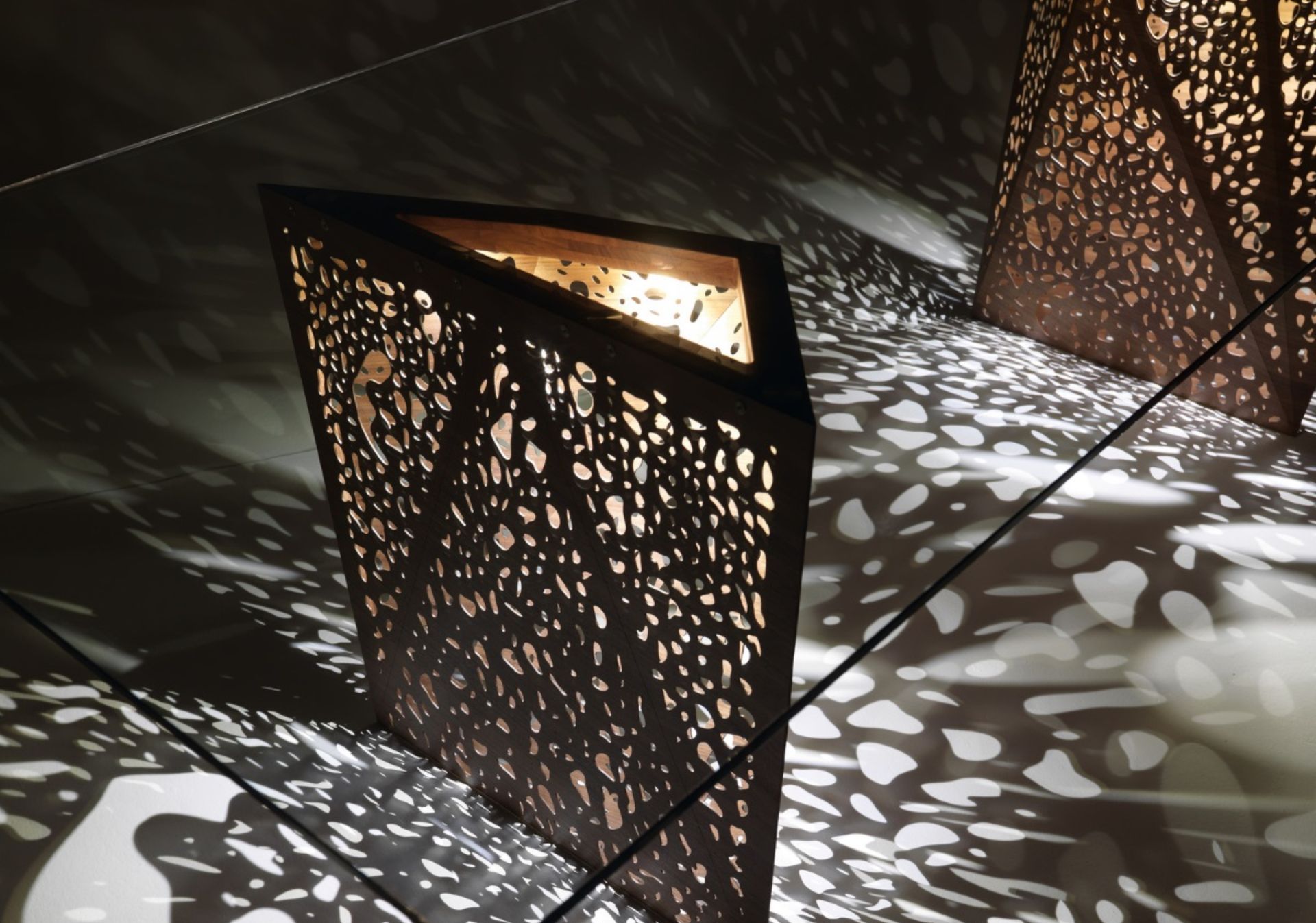 L’originalità e la lavorazione delle gambe sono le vere protagoniste del tavolo Riddled, che riprende il tema della porosità presente in molte architetture di Steven Holl.‎ I sottilissimi fogli di legno, piegati grazie a delle incisioni laser, rendono ancor più spettacolare questo progetto, che sembra una sfida alle leggi della fisica.‎ Le due gambe, simili a scultorei origami, permettono alla luce interna di trapassarle in una vera e propria esplosione di giochi d’ombre.‎
