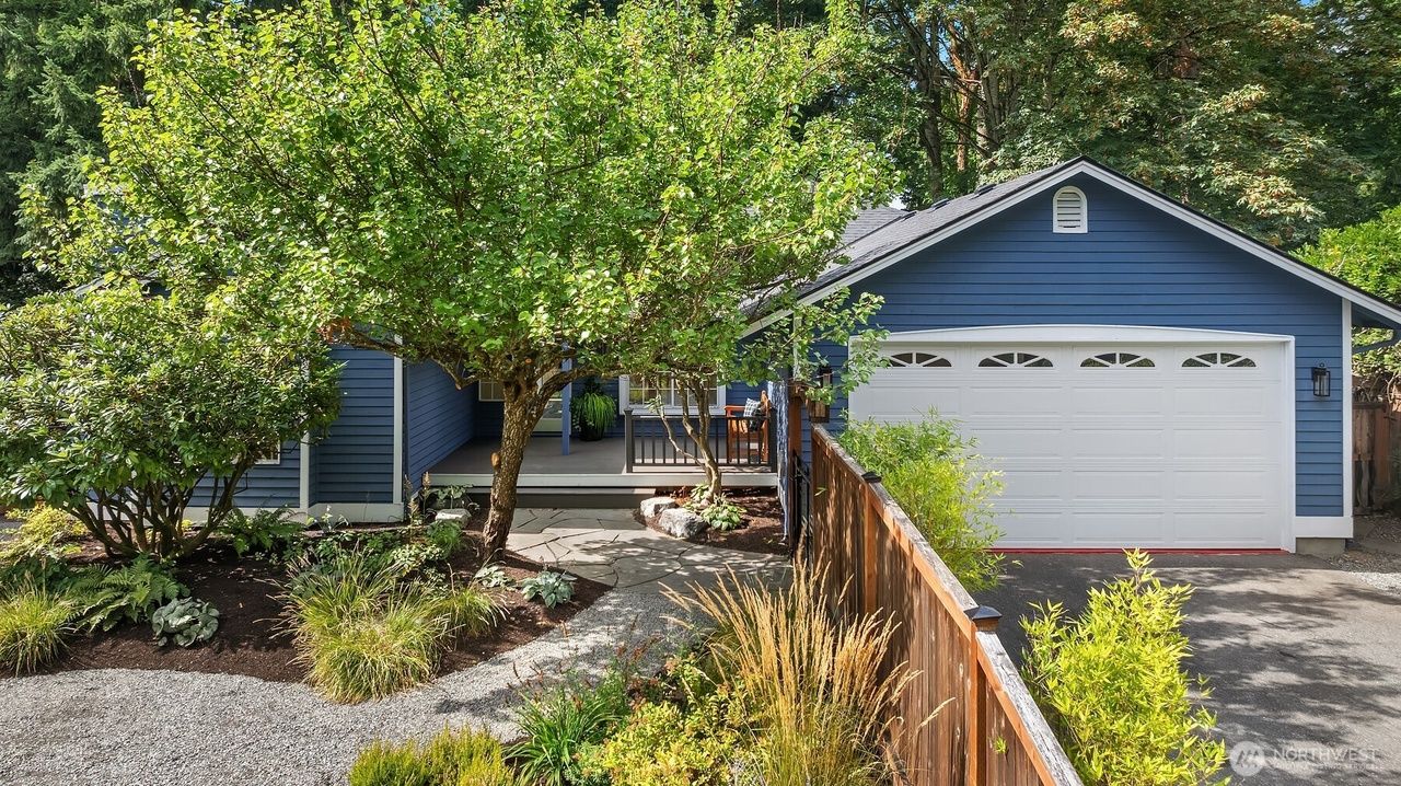 Blue house with white garage door, front porch, and landscaped yard.