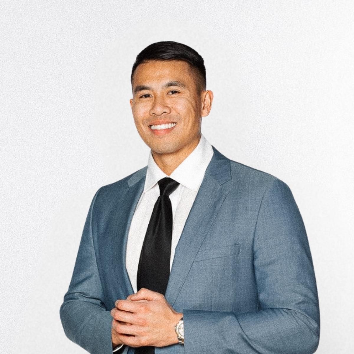 Eric Dang in a suit and tie smiling for the camera.