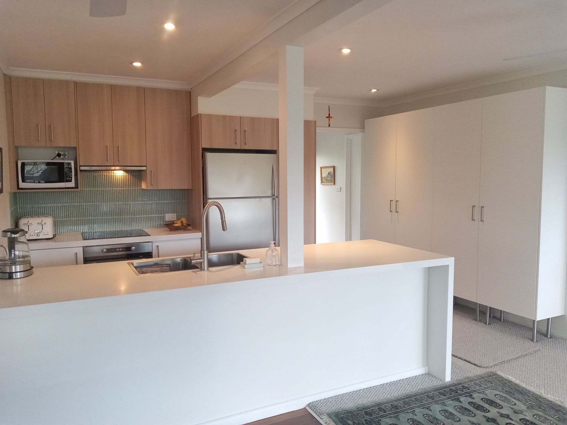 Modern kitchen with light wood cabinets, stainless steel appliances, and white island — Wards Kitchens in Berkeley Vale, NSW