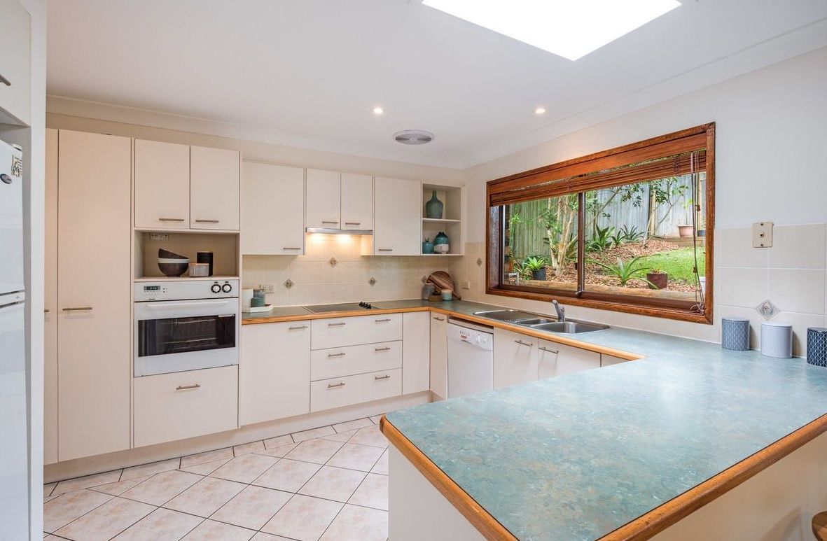 Cream-colored kitchen with a blue countertop, a large window looking onto greenery, and a skylight — Wards Kitchens in Berkeley Vale, NSW
