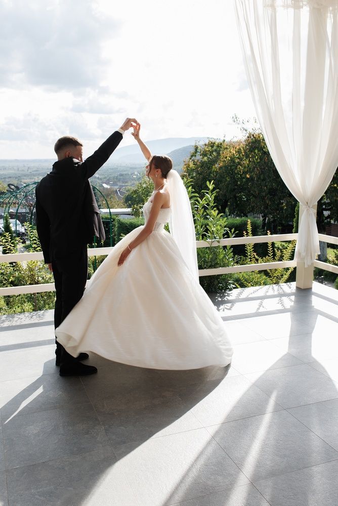 Bride and groom dancing on a sunlit terrace with ocean views