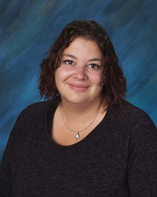 A woman wearing a black shirt and a necklace is smiling for a picture.