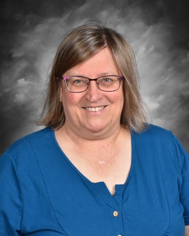 A woman wearing glasses and a sweater is posing for a picture.