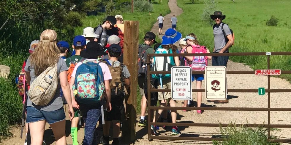 A group of children are walking down a dirt path.