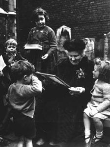 María Montessori is reading a book to a group of children.
