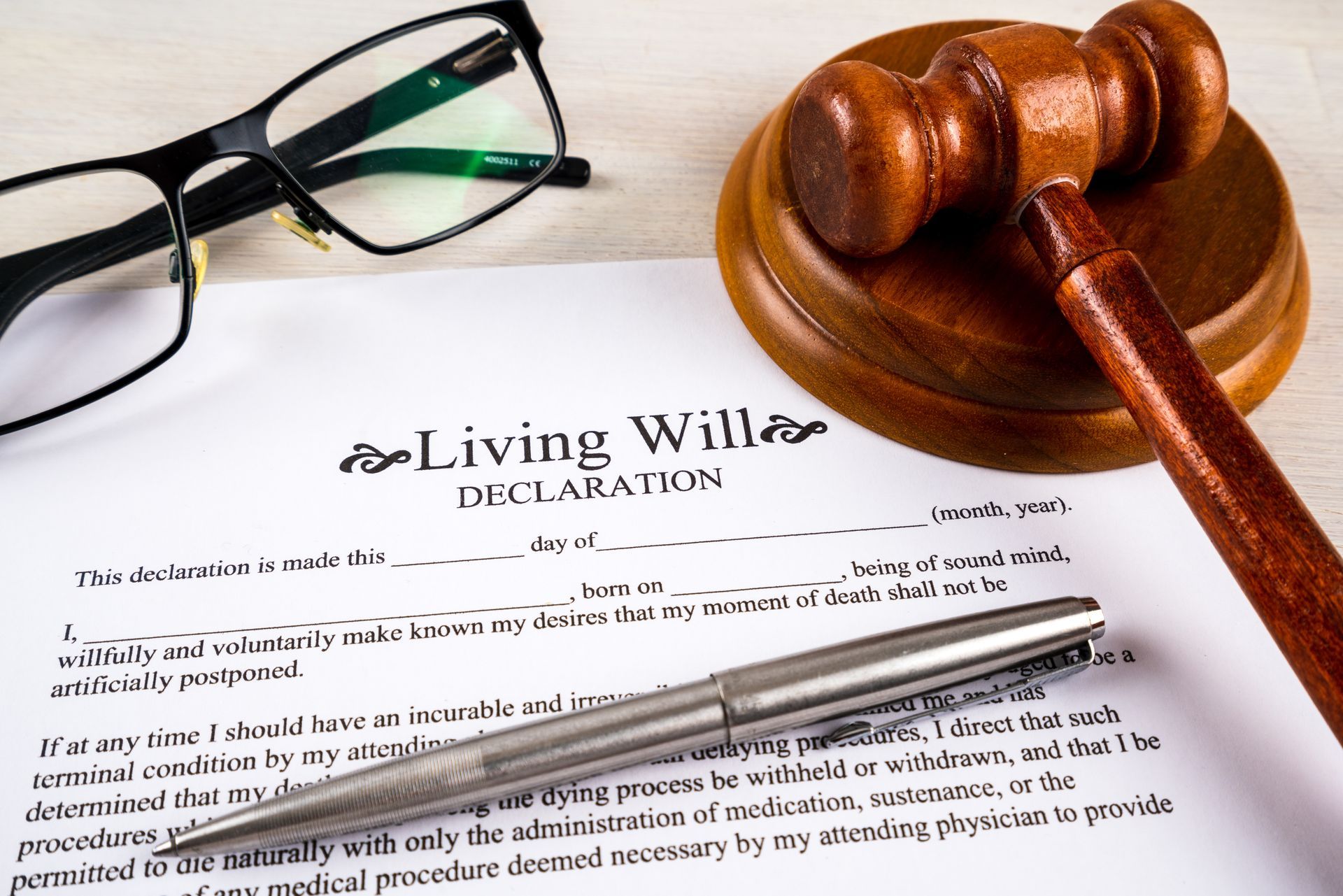 Living will declaration form with pen, gavel, and striking block, and glasses on top Living will declaration form with pen, gavel, and striking block, and glasses on top