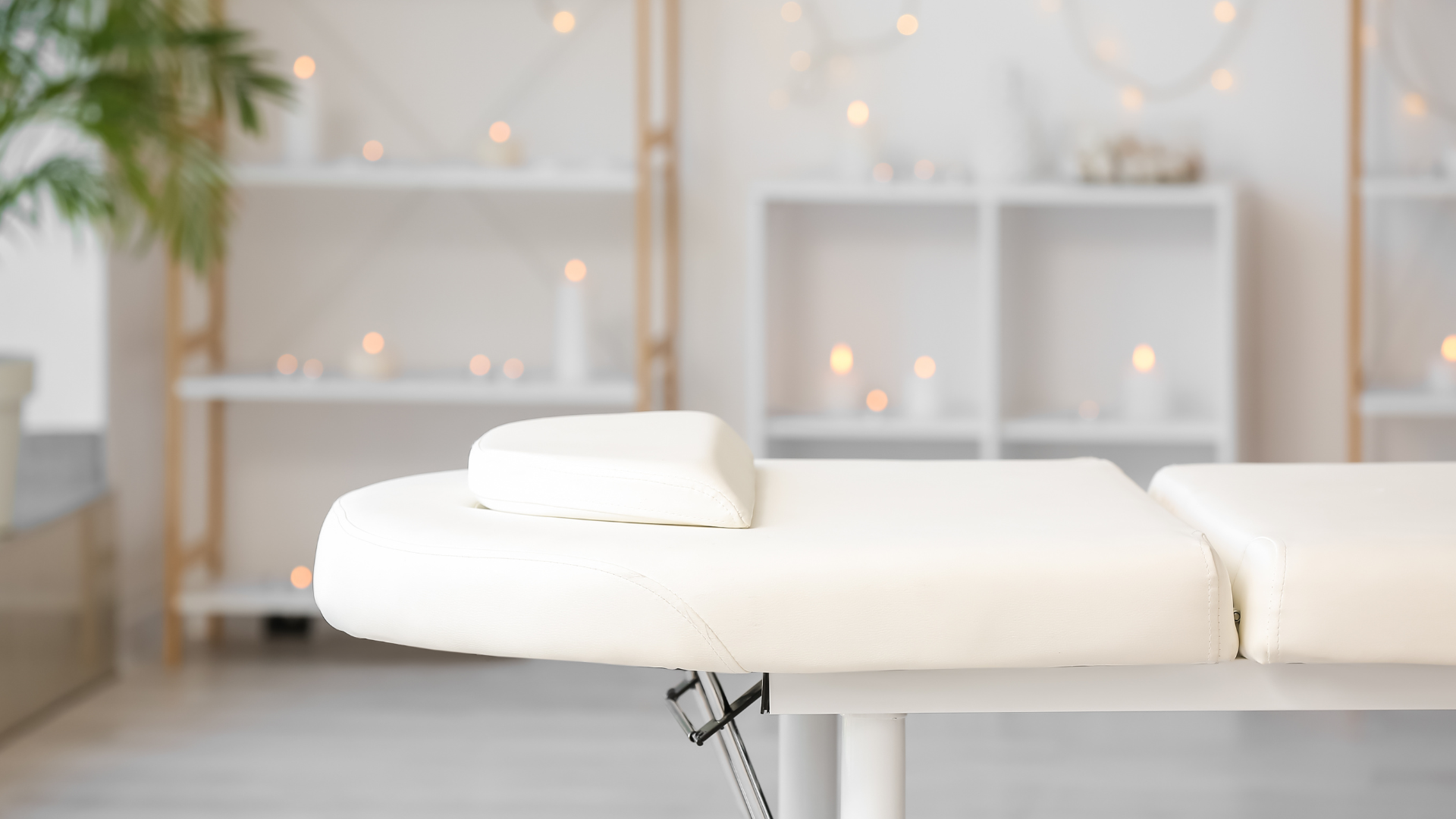 a white massage table in a room with candles on the shelves .