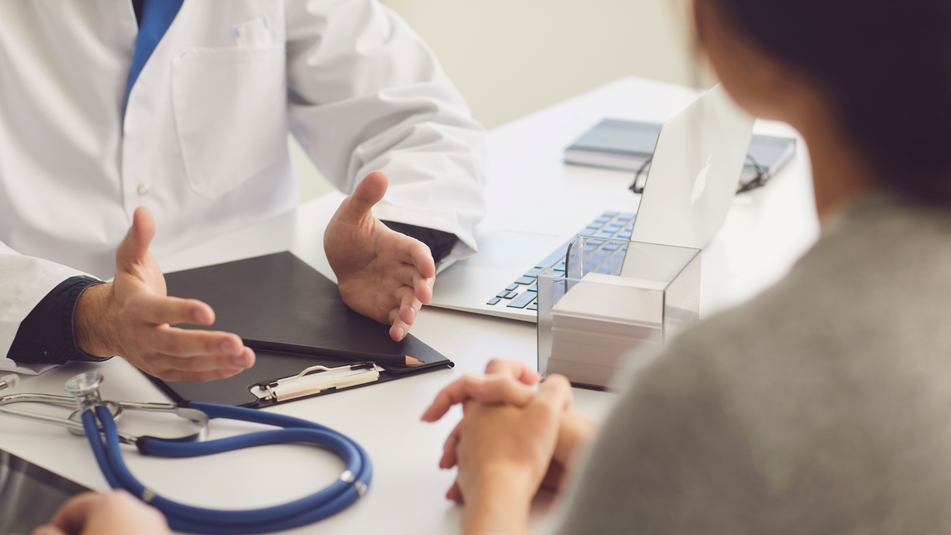 a doctor is talking to a patient while sitting at a desk .