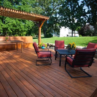 A wooden deck with chairs and a table under a pergola