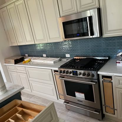 A kitchen with a stove , microwave , and cabinets.