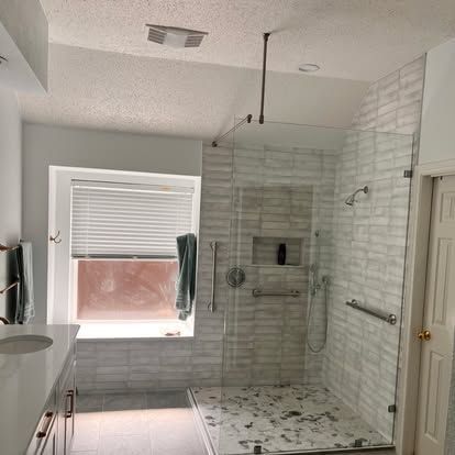 A bathroom with a walk in shower , sink , and window.