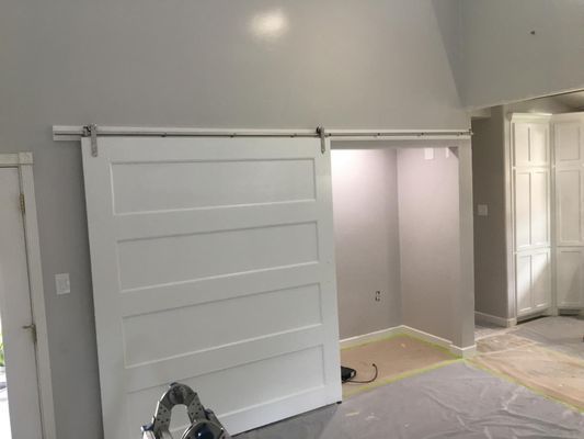 A white sliding barn door is hanging on a wall in a room.