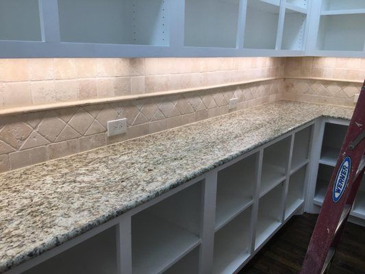 A kitchen with granite counter tops , white cabinets , and a ladder.