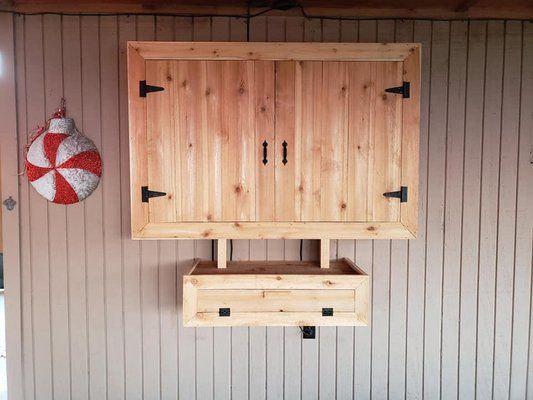 A wooden cabinet is hanging on a wall next to a candy cane.