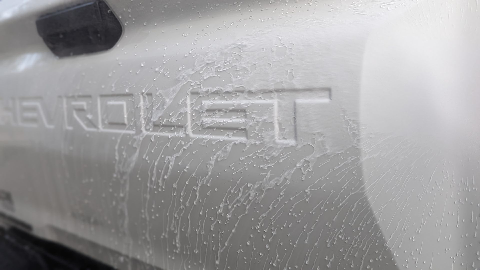 Close-up of a silver Chevrolet truck tailgate with the embossed