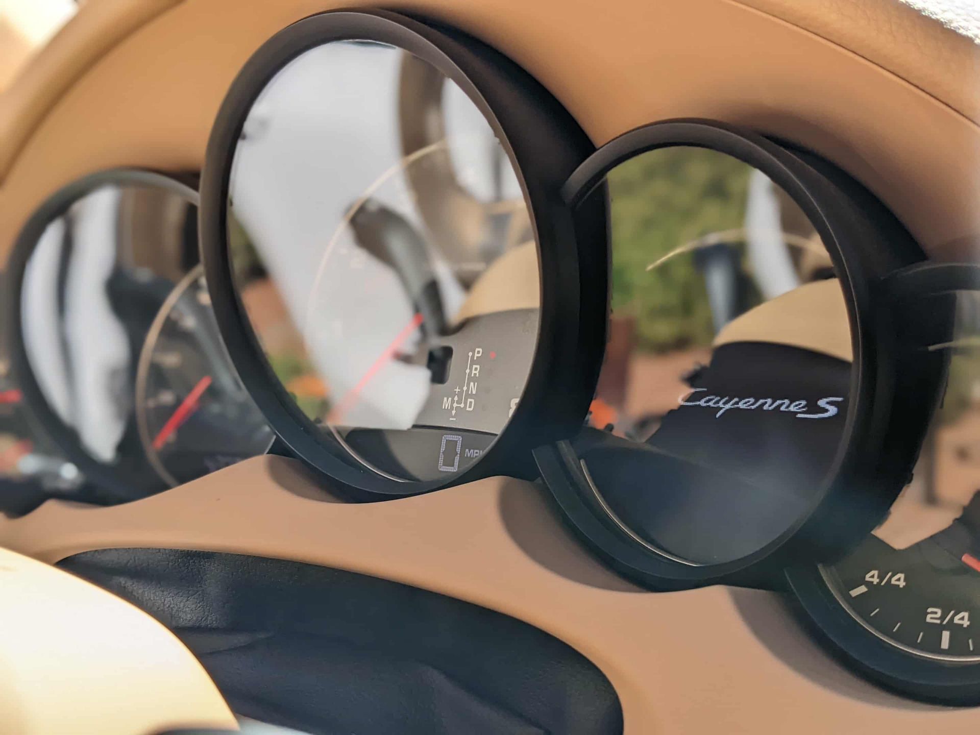 Dashboard gauges of a beige Porsche Cayenne S.