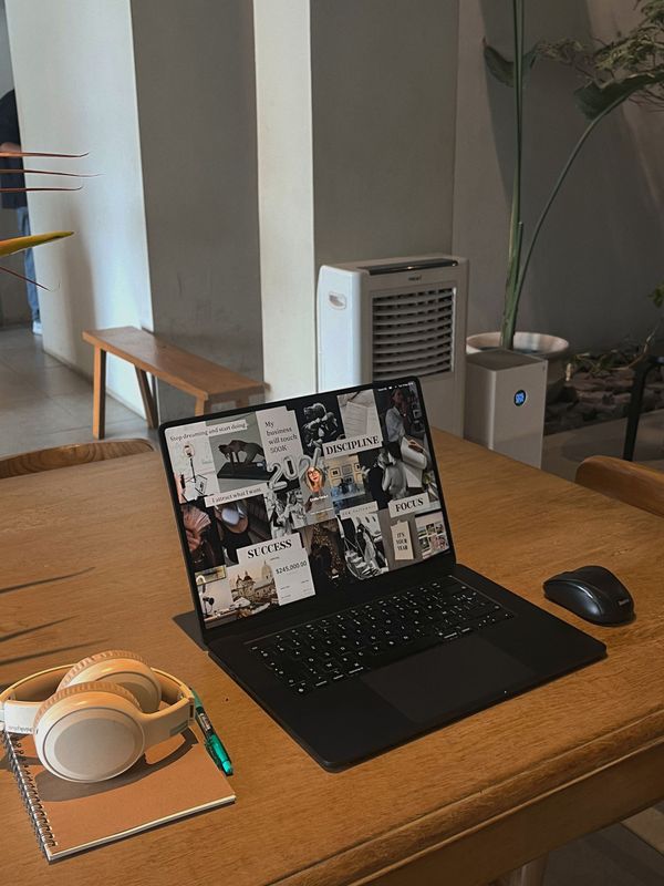 Laptop, notebook and headphones on a wooden desk