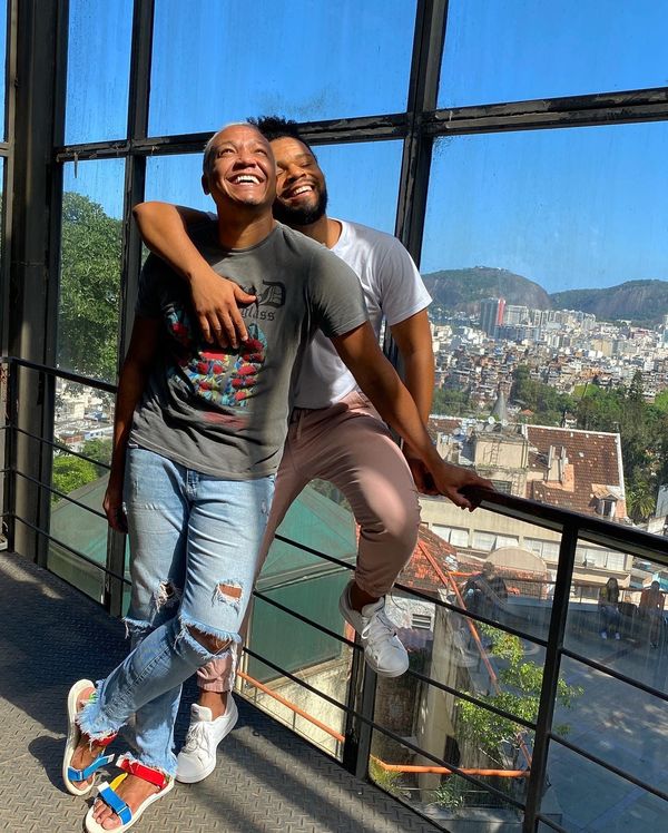 Two smiling friends embracing on a balcony above a city
